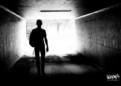 silhouette of teen walking through tunnel